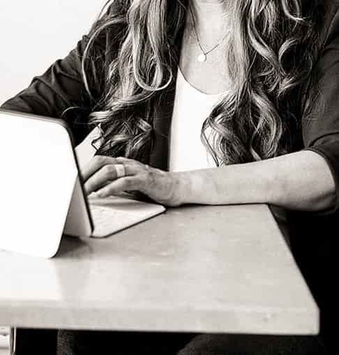 Emma Newman smiles as she sits in front of a tablet with an attached keyboard.